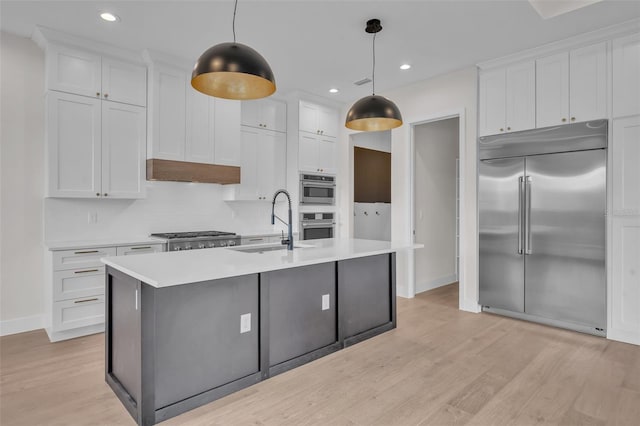 kitchen with stainless steel appliances, hanging light fixtures, light hardwood / wood-style floors, and white cabinetry