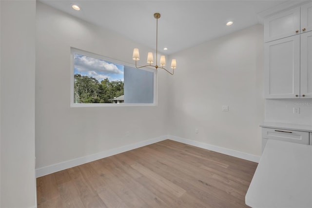 unfurnished dining area featuring light hardwood / wood-style flooring and a chandelier