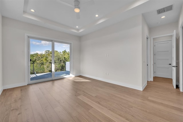 unfurnished room featuring a raised ceiling, light hardwood / wood-style floors, and ceiling fan