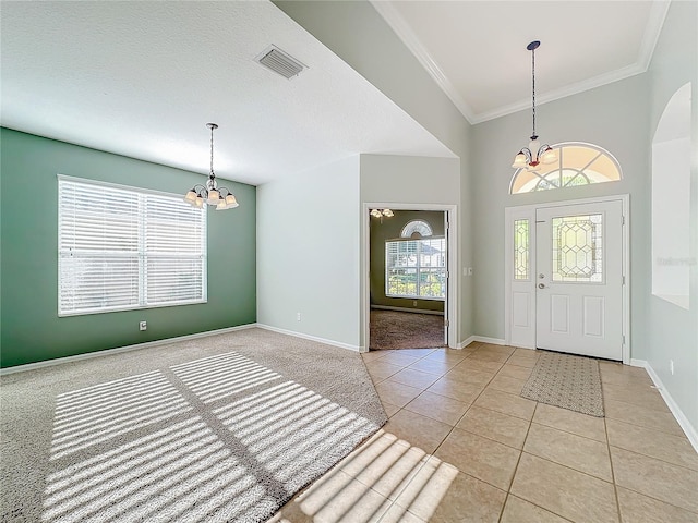 carpeted entryway with crown molding and an inviting chandelier