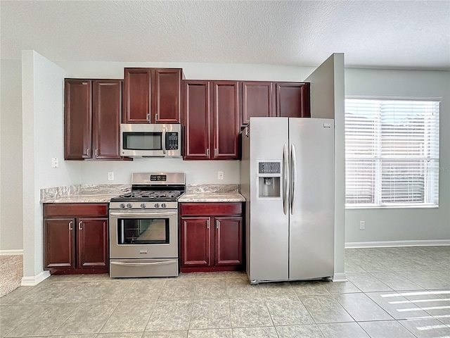 kitchen with appliances with stainless steel finishes, a textured ceiling, and light tile patterned floors