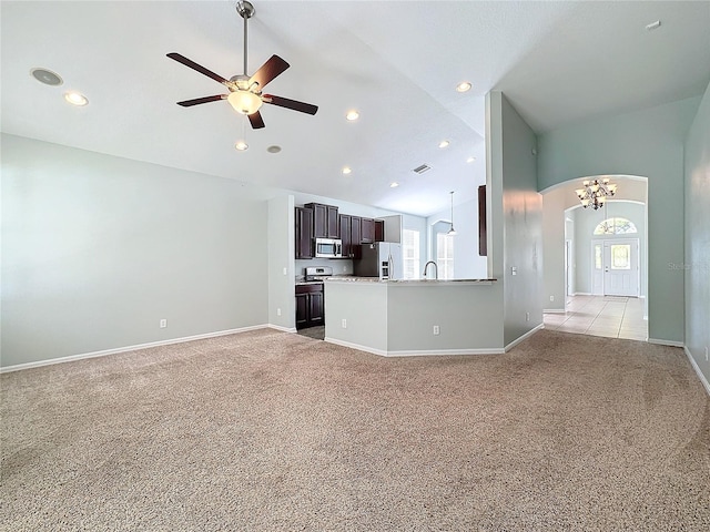 unfurnished living room featuring ceiling fan with notable chandelier, light carpet, and high vaulted ceiling