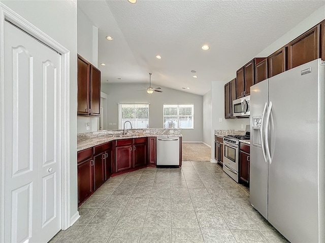 kitchen with vaulted ceiling, appliances with stainless steel finishes, kitchen peninsula, ceiling fan, and a textured ceiling