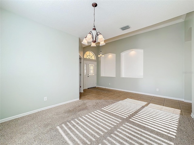 carpeted empty room featuring a notable chandelier and a textured ceiling