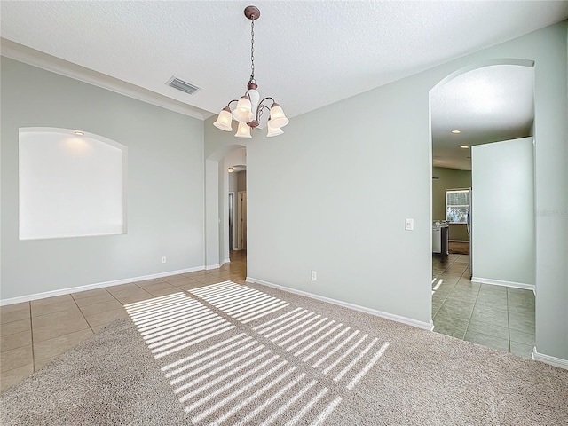 carpeted empty room with a textured ceiling and a chandelier