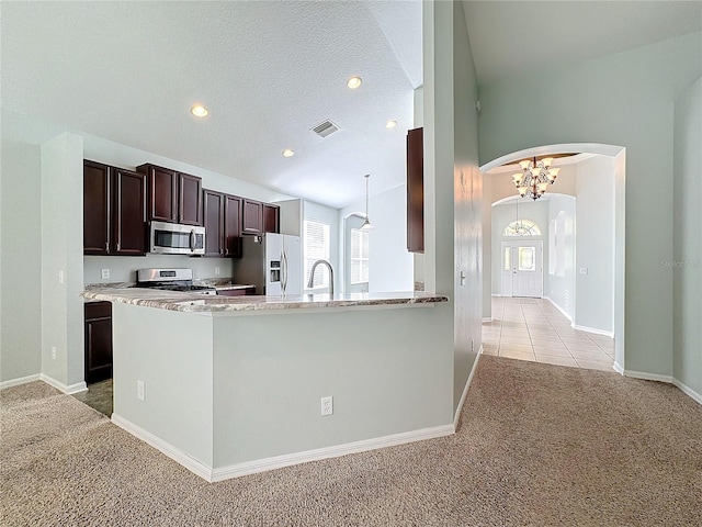 kitchen featuring a textured ceiling, a chandelier, decorative light fixtures, appliances with stainless steel finishes, and light colored carpet