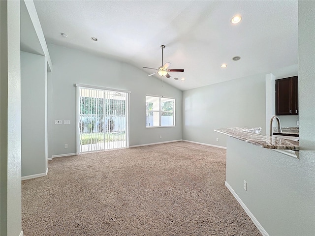 carpeted empty room with vaulted ceiling, sink, and ceiling fan