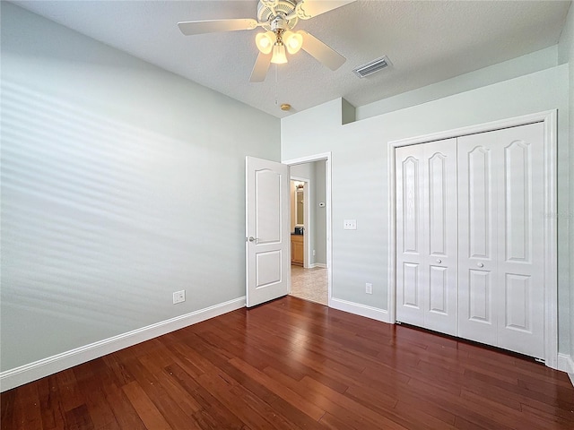 unfurnished bedroom featuring dark wood-type flooring, a closet, ceiling fan, and a textured ceiling