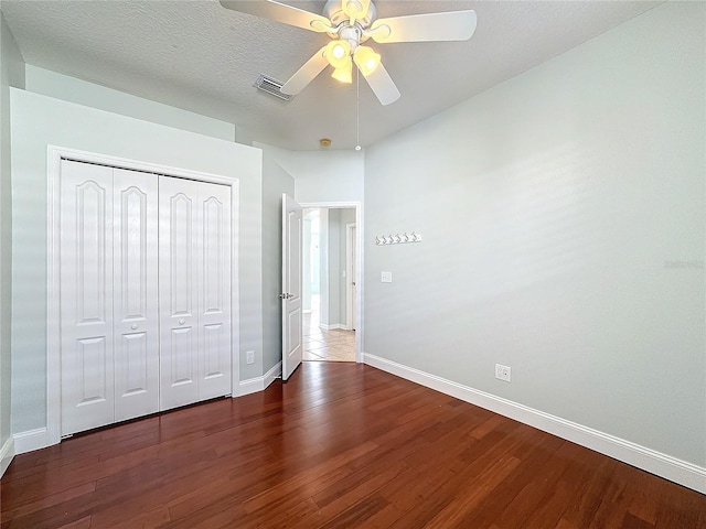 unfurnished bedroom featuring dark wood-type flooring, a closet, ceiling fan, and a textured ceiling