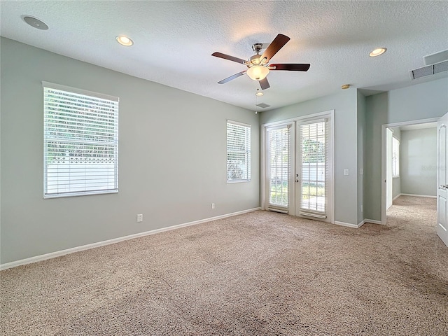 carpeted empty room with ceiling fan and a textured ceiling