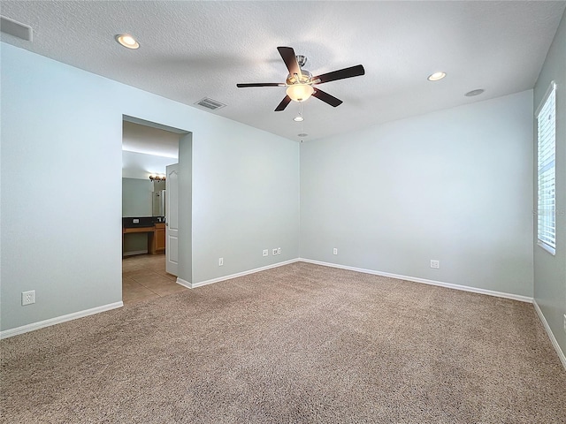 carpeted spare room featuring ceiling fan and a textured ceiling