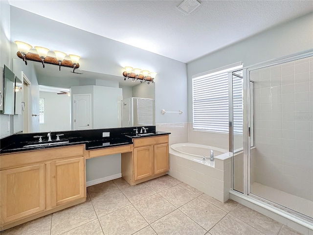 bathroom featuring tile patterned flooring, independent shower and bath, a textured ceiling, and vanity