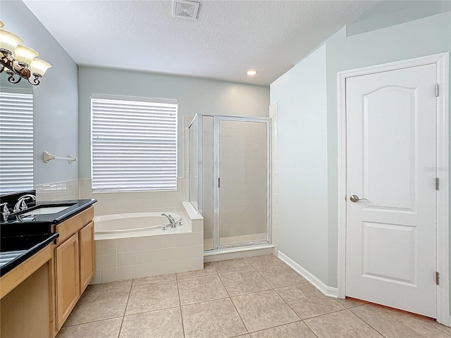 bathroom with a textured ceiling, vanity, tile patterned floors, and plus walk in shower