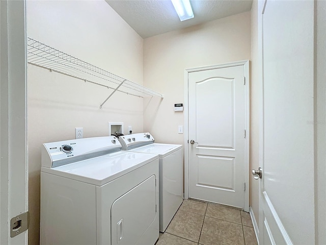 clothes washing area with washing machine and clothes dryer, light tile patterned floors, and a textured ceiling