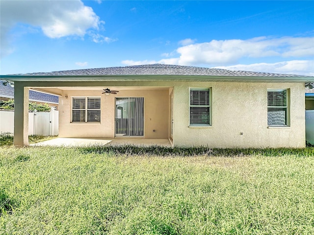 back of property with ceiling fan, a yard, and a patio