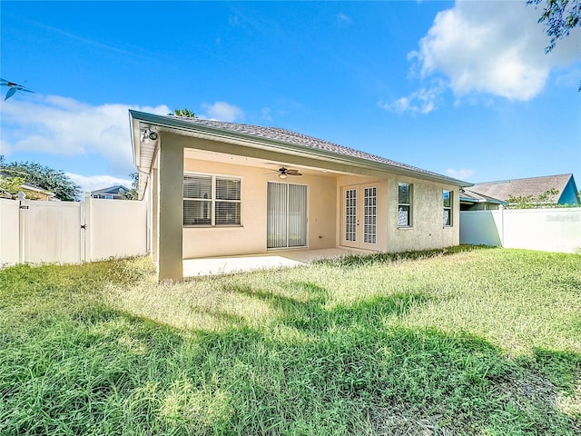 back of property featuring ceiling fan, a lawn, and a patio