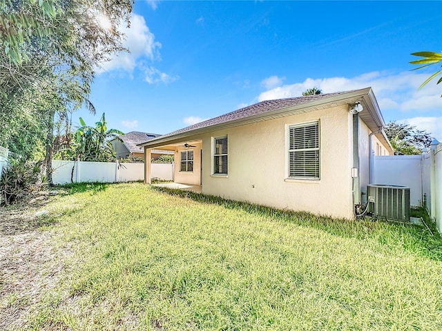 back of property featuring cooling unit and a yard