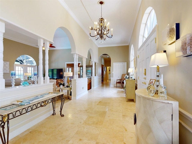 foyer entrance with an inviting chandelier, crown molding, ornate columns, and a towering ceiling