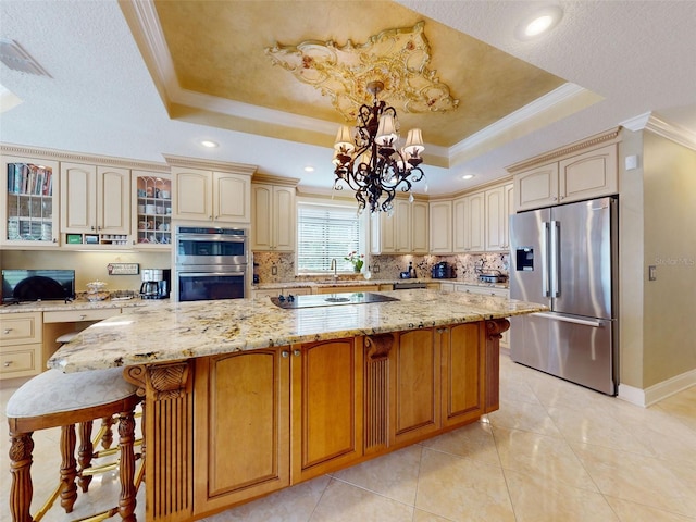 kitchen featuring pendant lighting, a kitchen island, a raised ceiling, and appliances with stainless steel finishes