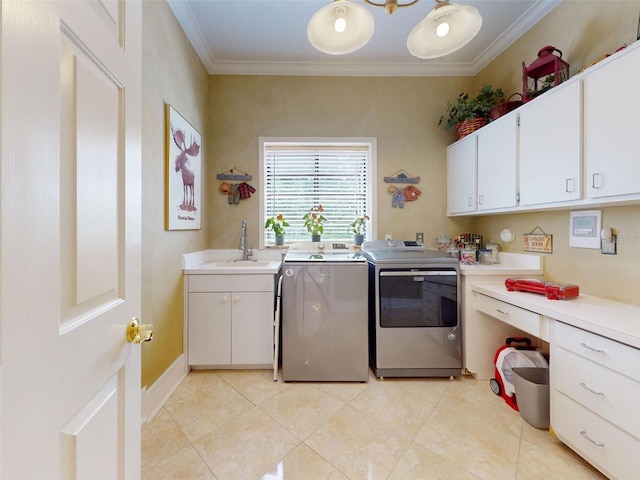 laundry area featuring sink, crown molding, light tile patterned floors, washing machine and dryer, and cabinets