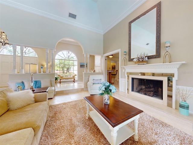 living room featuring a towering ceiling, ornamental molding, and decorative columns