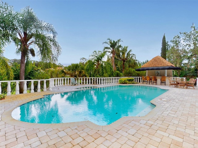 view of swimming pool featuring an outdoor bar and a patio area