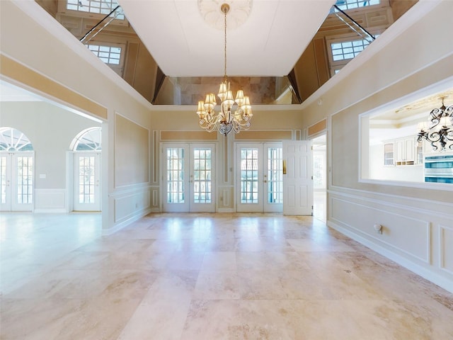 spare room with french doors, a high ceiling, and a notable chandelier