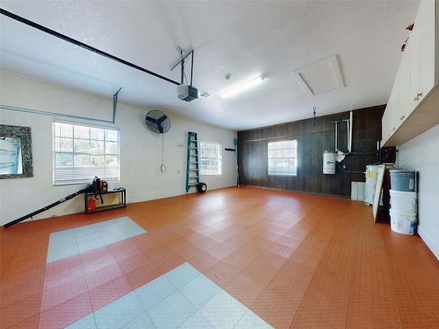 garage featuring a garage door opener, gas water heater, and wooden walls