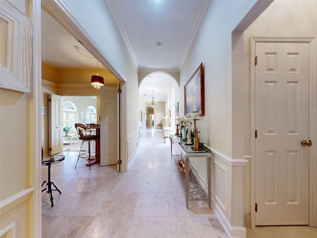 corridor with an inviting chandelier and crown molding