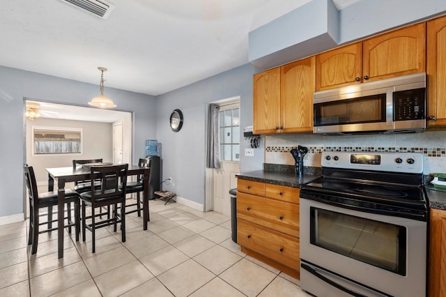 kitchen featuring hanging light fixtures, stainless steel appliances, light tile patterned flooring, and tasteful backsplash