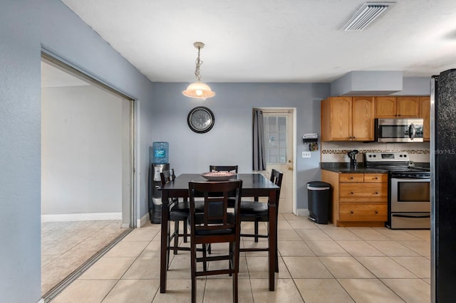 kitchen with pendant lighting, tasteful backsplash, light tile patterned floors, and stainless steel appliances