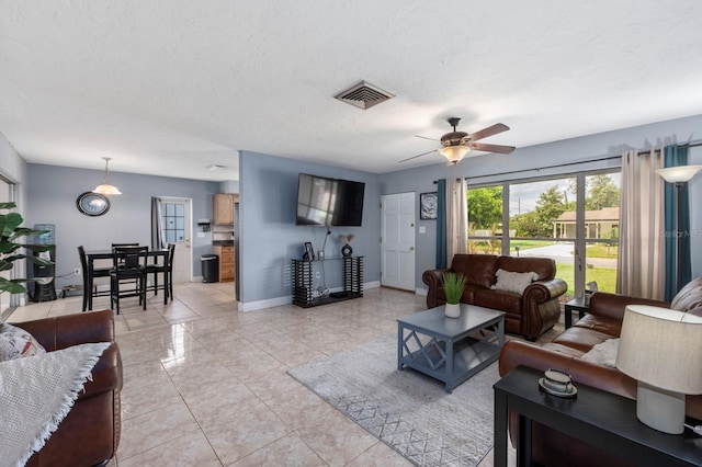 tiled living room with ceiling fan and a textured ceiling