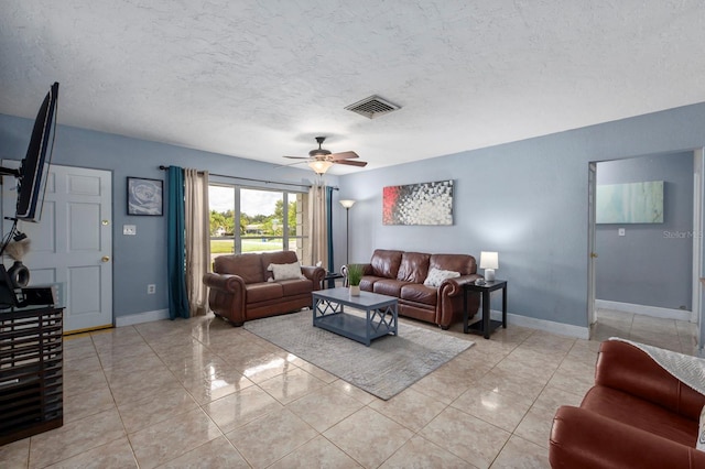 living room featuring a textured ceiling, ceiling fan, and light tile patterned flooring