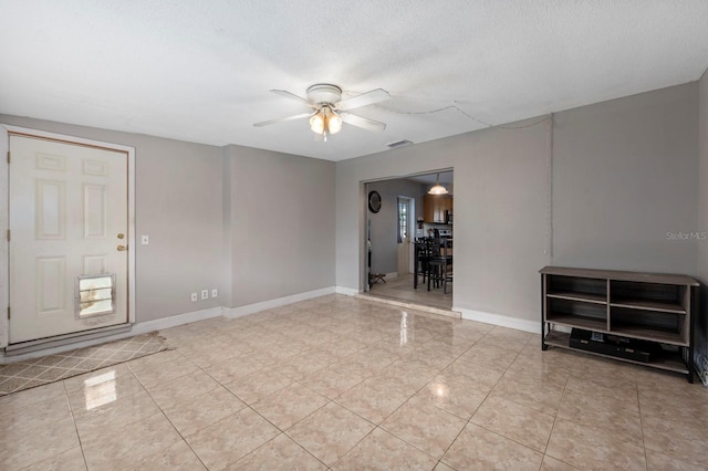 unfurnished living room featuring ceiling fan and a textured ceiling