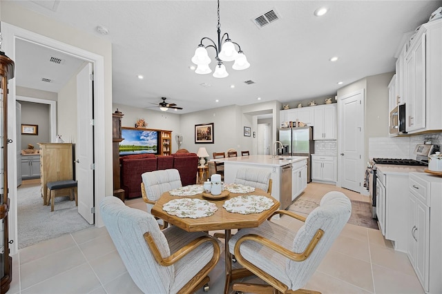 dining room featuring ceiling fan with notable chandelier, light tile patterned floors, and sink