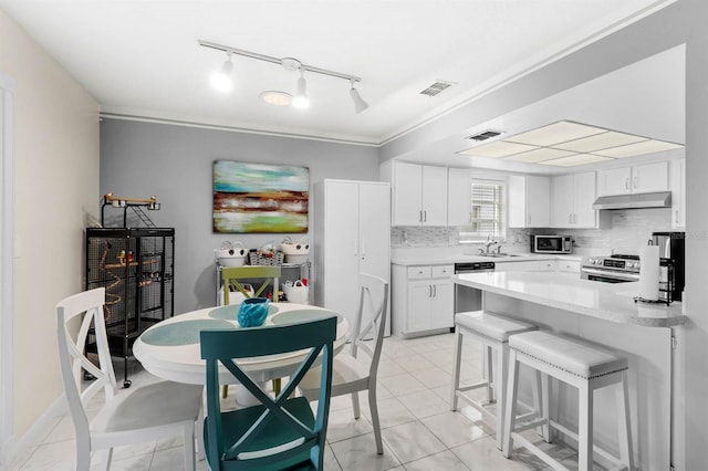 kitchen with white cabinetry, a kitchen bar, light tile patterned floors, stainless steel appliances, and sink