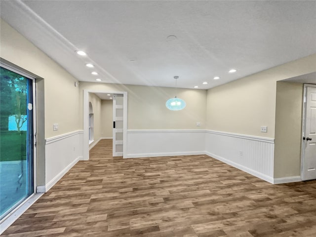 interior space with a textured ceiling, a healthy amount of sunlight, and hardwood / wood-style floors