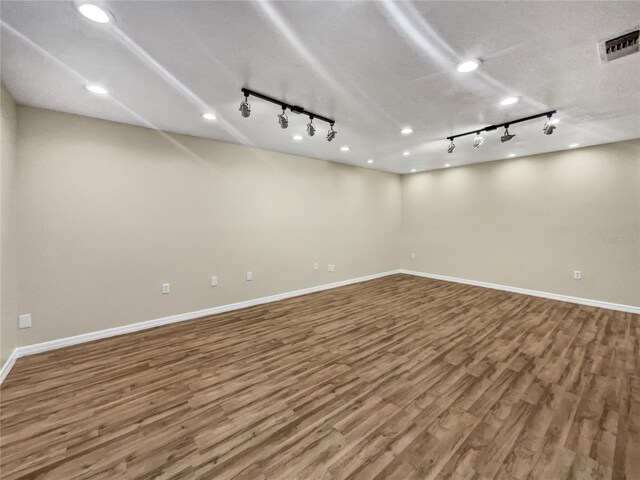 basement with track lighting, wood-type flooring, and a textured ceiling