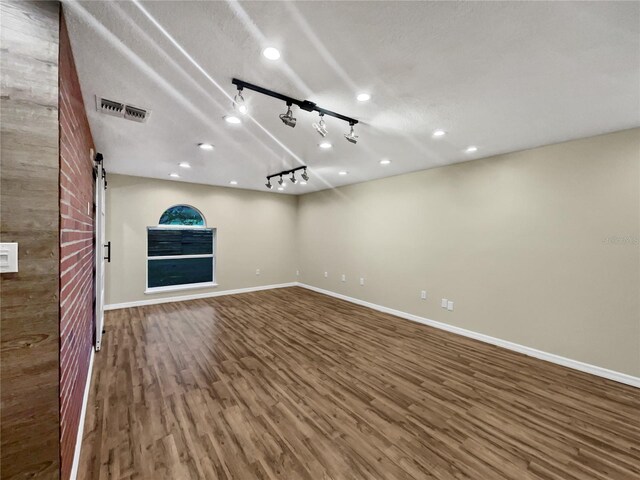 interior space featuring a textured ceiling, rail lighting, hardwood / wood-style floors, and a barn door