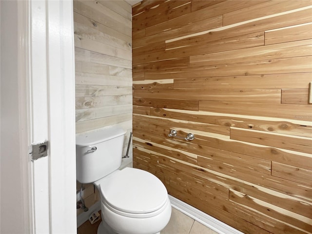 bathroom featuring tile patterned floors, toilet, and wooden walls