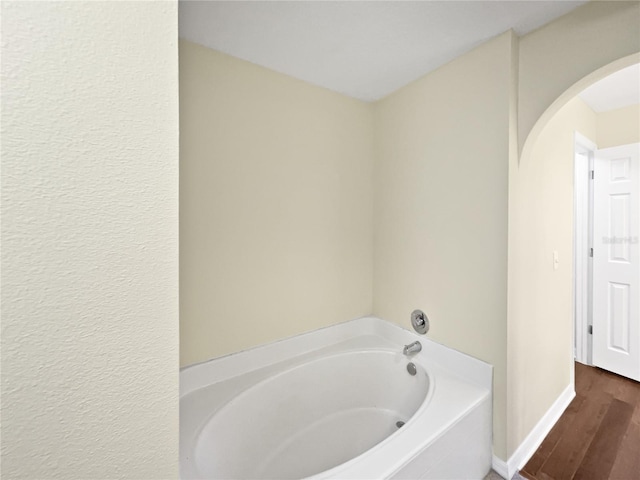 bathroom with a tub and hardwood / wood-style flooring