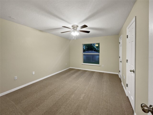 carpeted spare room featuring a textured ceiling and ceiling fan