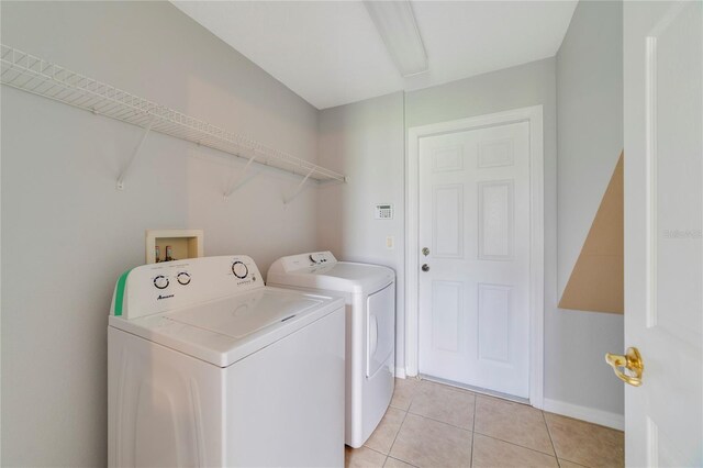 laundry area with washer and clothes dryer and light tile patterned flooring