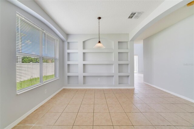 unfurnished room featuring built in features, a textured ceiling, and light tile patterned flooring