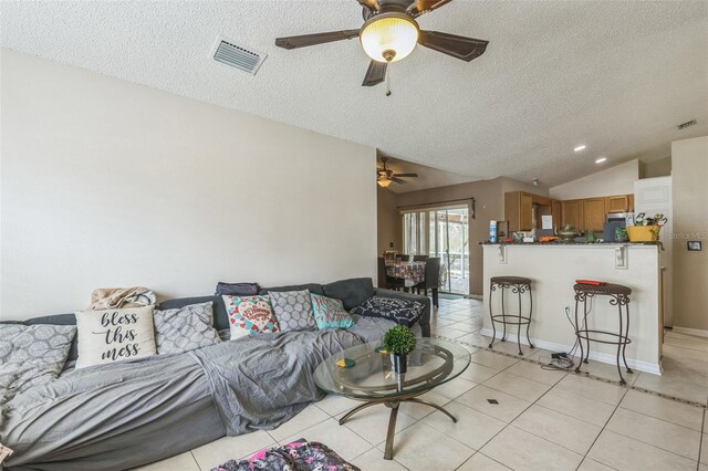 living room featuring vaulted ceiling, a textured ceiling, light tile patterned flooring, and ceiling fan