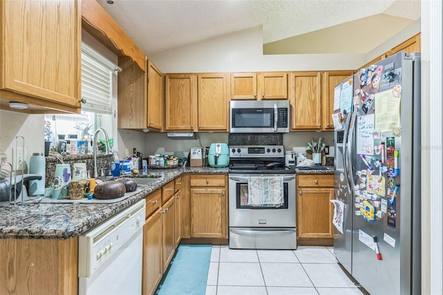 kitchen with vaulted ceiling, a textured ceiling, stainless steel appliances, and light tile patterned flooring