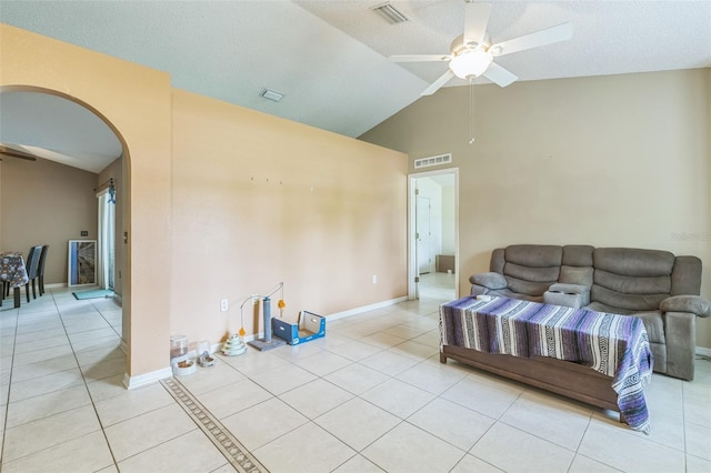 living room with a textured ceiling, ceiling fan, light tile patterned floors, and vaulted ceiling