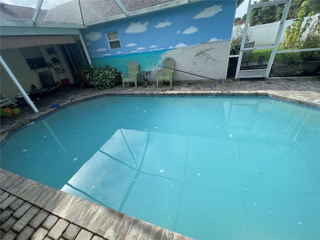 view of swimming pool featuring a patio and glass enclosure