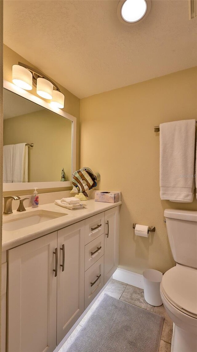 bathroom featuring a textured ceiling, vanity, toilet, and tile patterned flooring