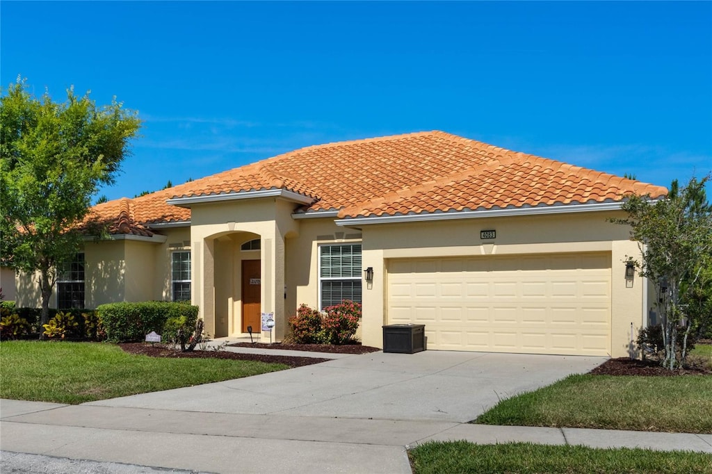 mediterranean / spanish home featuring a front lawn and a garage